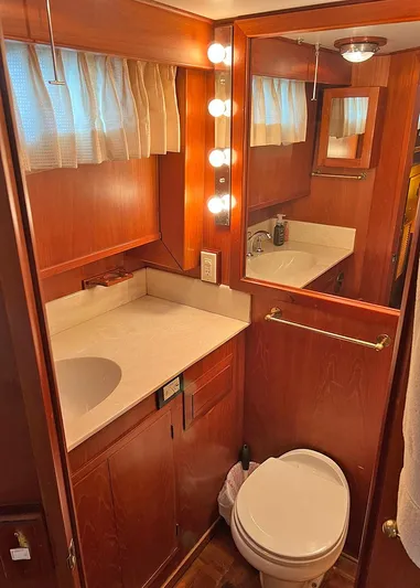  Yacht Photos Pics 1987 DeFever Tri-Cabin bathroom with wood cabinetry, mirror, and vanity lighting.