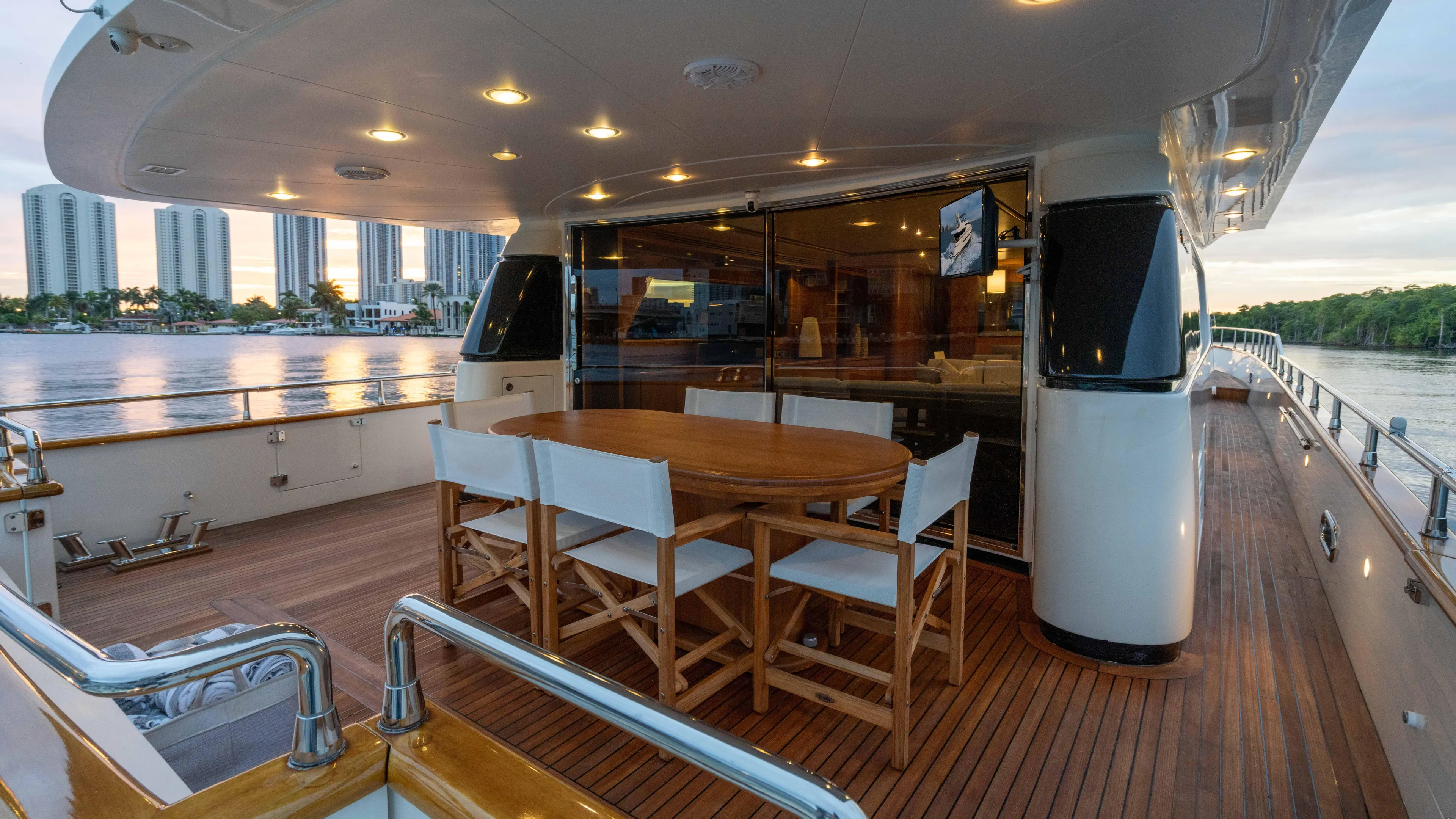 Losand Yacht Photos Pics Luxurious 2005 Sanlorenzo SL82 yacht deck with dining area, overlooking waterfront skyline.