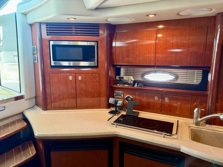 Great Escape Yacht Photos Pics 2004 Sea Ray 390 Sundancer yacht kitchen with microwave, stove, and wooden cabinetry.