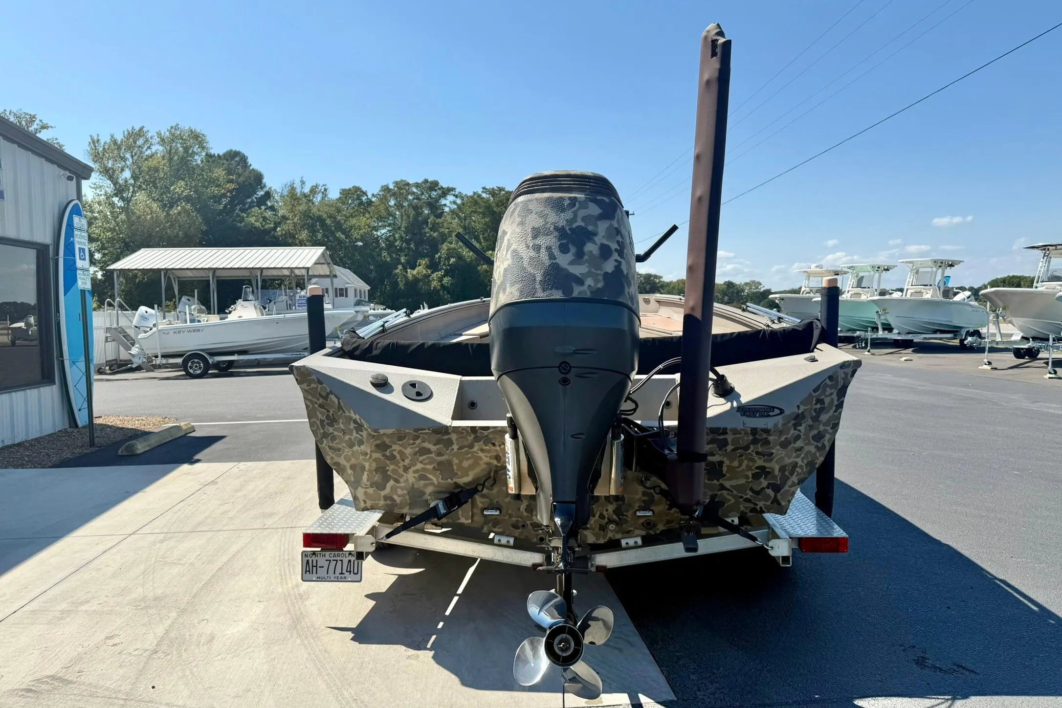 2019 Excel 230 Bay Pro boat with camouflage design, parked on a trailer at a marina.