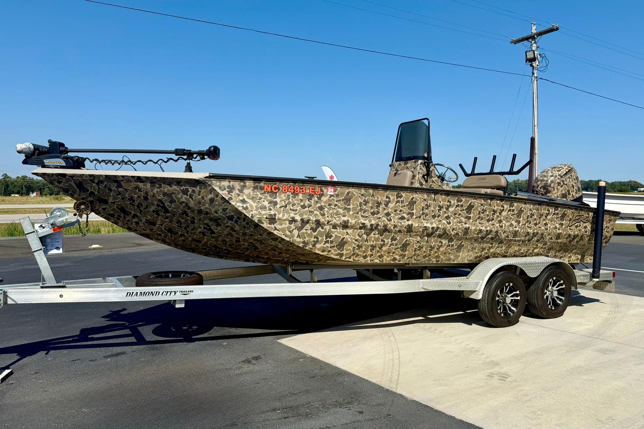 2019 Excel 230 Bay Pro boat with camouflage design on a trailer, parked outdoors.