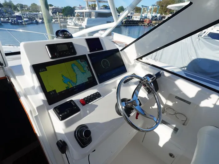  Yacht Photos Pics 2024 Albemarle 30 Express helm with navigation screens and steering wheel, docked at marina.