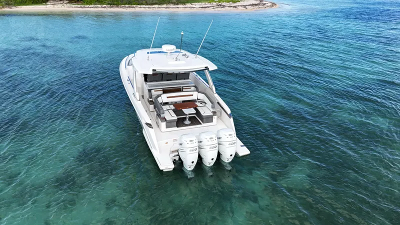  Yacht Photos Pics Aerial view of 2020 Tiara Yachts 38 LS on clear blue water near a shoreline.