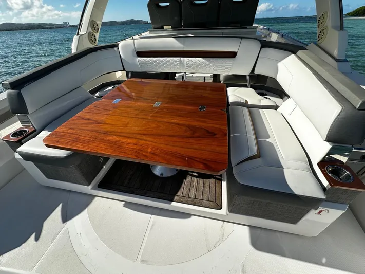  Yacht Photos Pics 2020 Tiara Yachts 38 LS interior with elegant seating and wooden table, ocean backdrop.