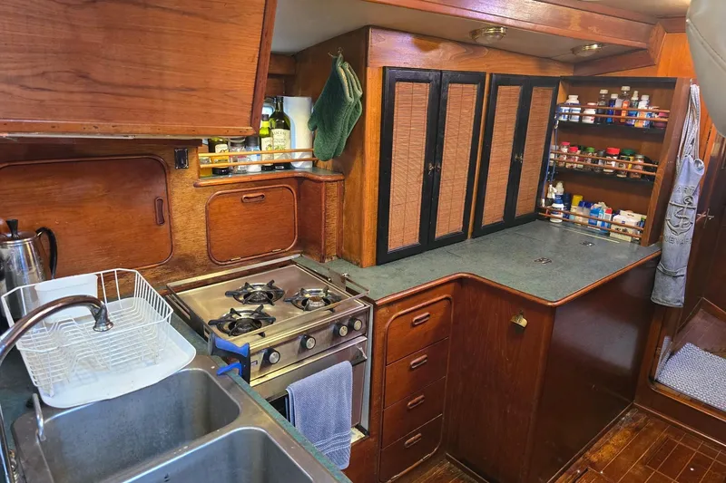 At Last Yacht Photos Pics 1982 Irwin 52 yacht kitchen with stove, sink, and wooden cabinetry.