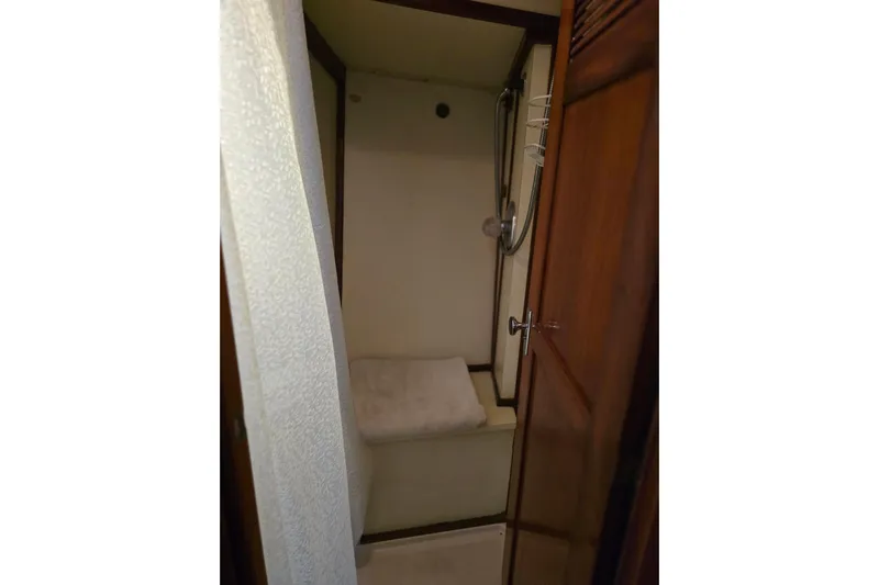 At Last Yacht Photos Pics Compact shower area in a 1982 Irwin 52 sailboat, featuring wooden accents and a handheld showerhead.