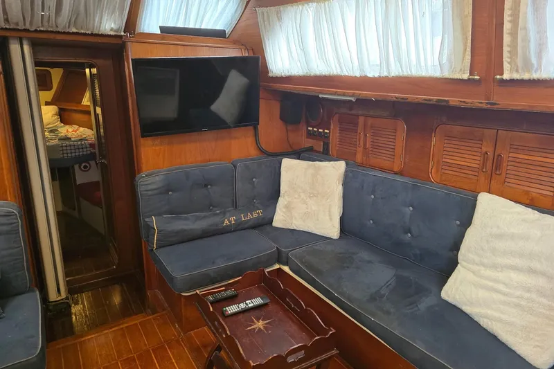 At Last Yacht Photos Pics Cozy interior of 1982 Irwin 52 yacht with blue seating and wooden accents.