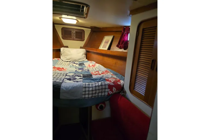 At Last Yacht Photos Pics Cozy cabin interior of 1982 Irwin 52 sailboat with colorful bedding and wooden accents.