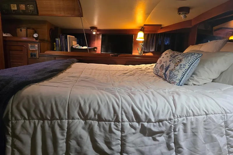 At Last Yacht Photos Pics Cozy cabin bedroom in a 1982 Irwin 52 sailboat with plush bedding and warm lighting.