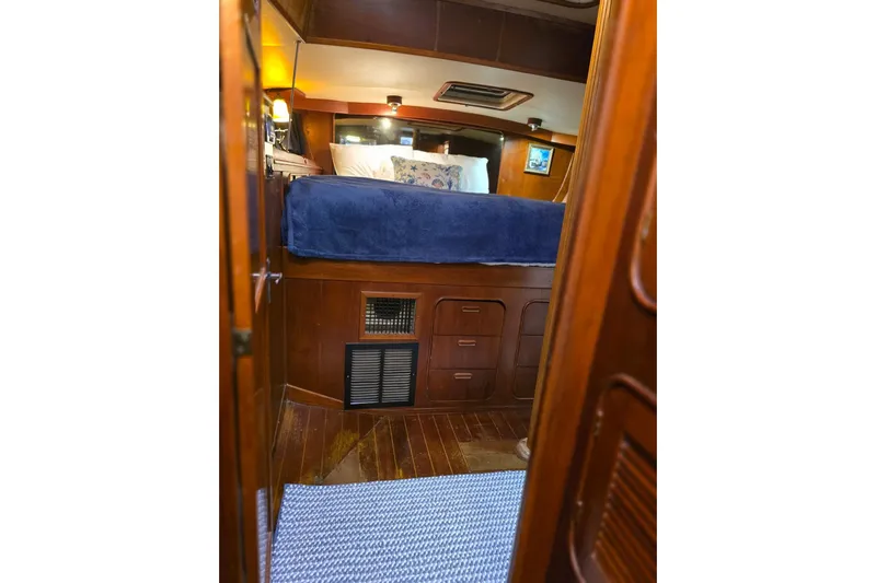 At Last Yacht Photos Pics Cozy cabin interior of 1982 Irwin 52 sailboat with wooden furnishings and blue bedding.