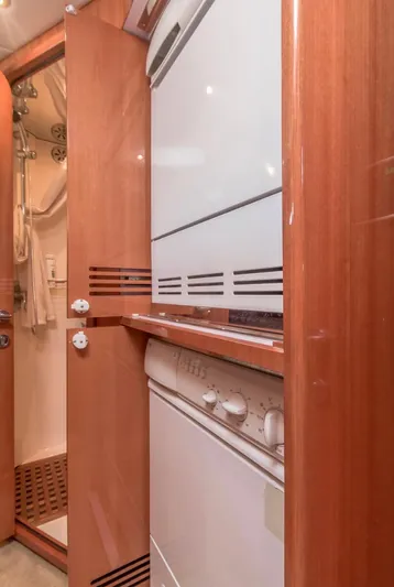  Yacht Photos Pics Wood-paneled laundry area with stacked washer and dryer on a 2005 Johnson 70 yacht.