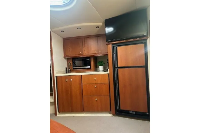  Yacht Photos Pics 2001 Cruisers Yachts 3870 interior with kitchenette, wooden cabinets, fridge, and TV.