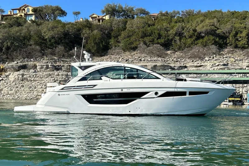 2021 Cruisers Yachts 50 Cantius Yacht Photos Pics 2021 Cruisers Yachts 50 Cantius on serene water, with lush greenery in the background.