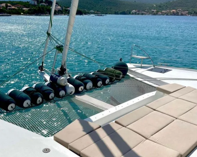 Elba 45 Yacht Photos Pics Fountaine Pajot Catamaran Elba 45, 2021, with sunbathing area and netting over turquoise water.