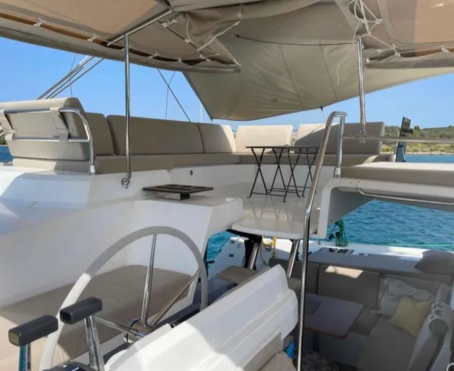 Elba 45 Yacht Photos Pics 2021 Fountaine Pajot Catamaran Elba 45 interior with seating and table, under canopy.