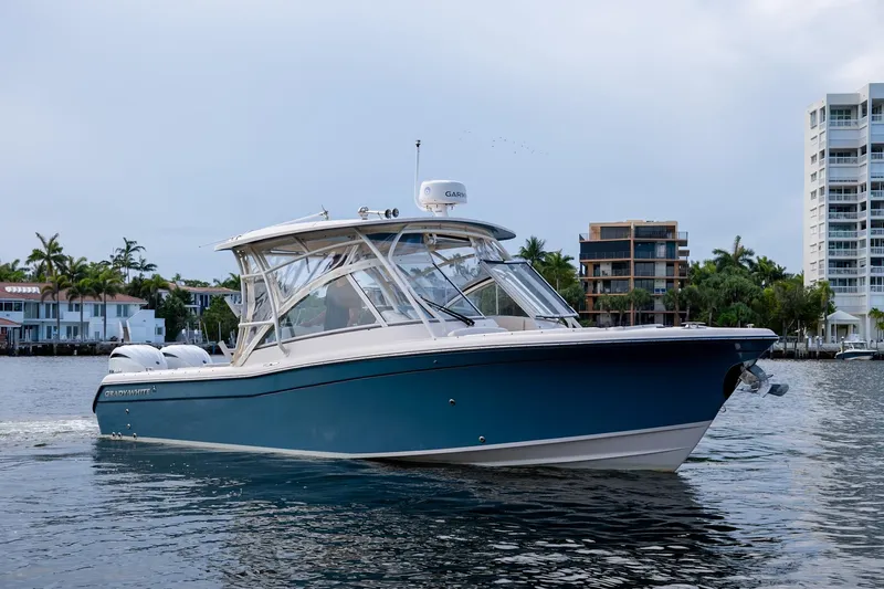  Yacht Photos Pics 2022 Grady-White Freedom 285 boat cruising on calm water near modern buildings.