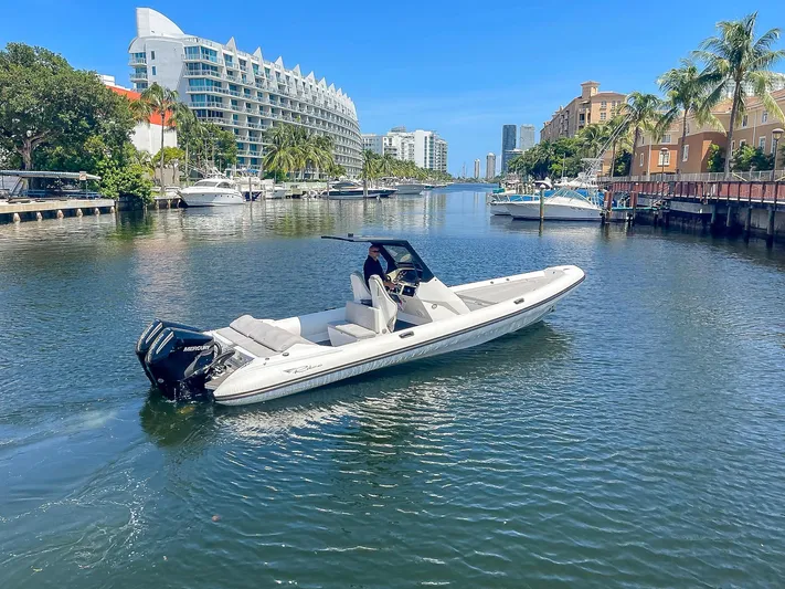  Yacht Photos Pics 2025 Ribco Venom 30 boat cruising in a scenic urban waterway with modern buildings.
