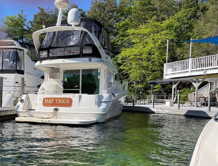 Hat Trick Yacht Photos Pics 2003 Sea Ray 400 Sedan Bridge yacht docked near lush greenery.