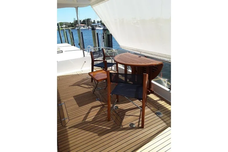 Endless Summer Yacht Photos Pics Cockpit Deck of 2008 Offshore Yachts 62 Flushdeck with wooden chairs and table.