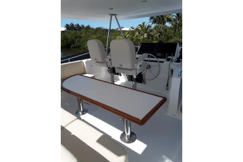 Endless Summer Yacht Photos Pics Flybridge helm with seating and table, surrounded by lush greenery.