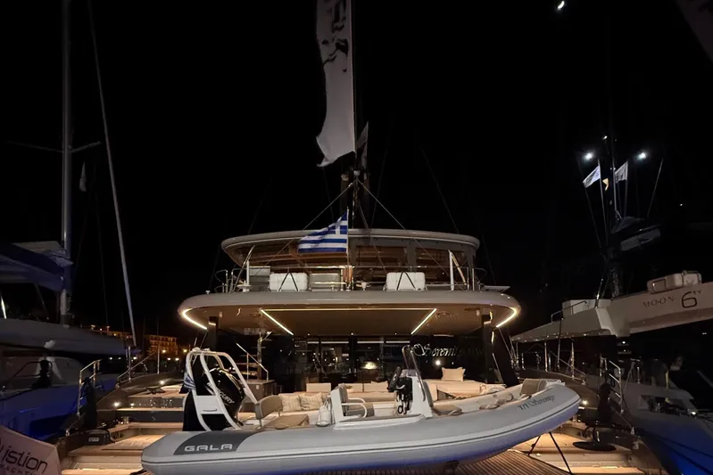 Serenity Yacht Photos Pics Luxurious 2024 Sunreef 60 yacht illuminated at night, docked with a tender boat.