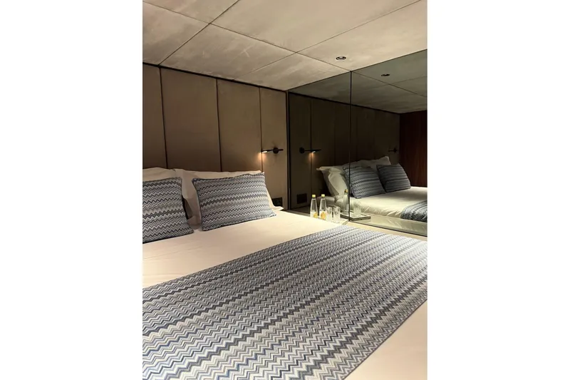 Serenity Yacht Photos Pics Luxurious bedroom interior of 2024 Sunreef 60 yacht with modern decor and mirrored wall.