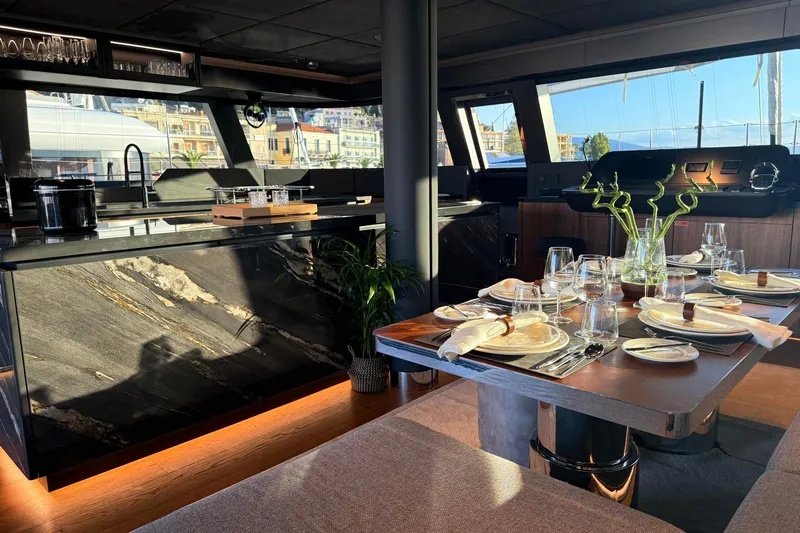 Serenity Yacht Photos Pics Luxurious interior of 2024 Sunreef 60 yacht with elegant dining setup and modern kitchen.