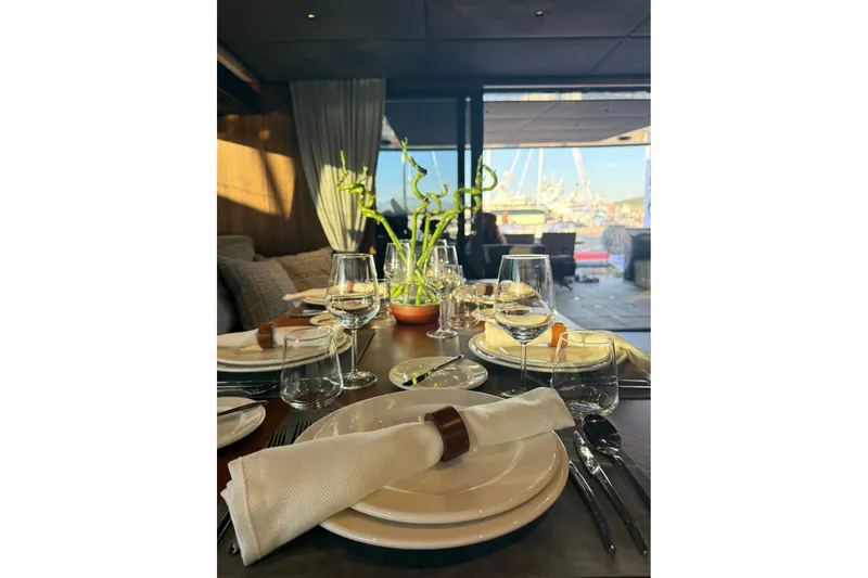 Serenity Yacht Photos Pics Elegant dining setup on 2024 Sunreef 60 yacht, featuring glassware and bamboo centerpiece.