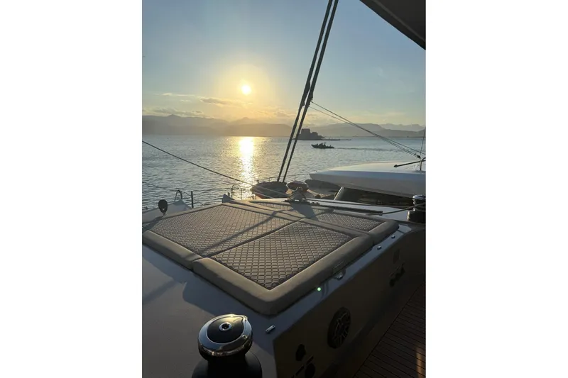 Serenity Yacht Photos Pics Sunset view from 2024 Sunreef 60 yacht deck, overlooking calm sea and distant mountains.