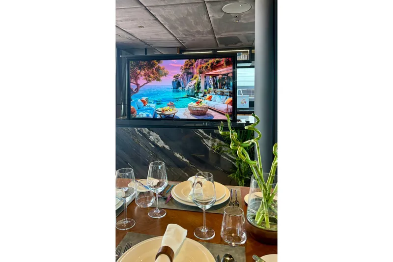 Serenity Yacht Photos Pics Luxurious dining setup on 2024 Sunreef 60 yacht with elegant tableware and scenic screen display.