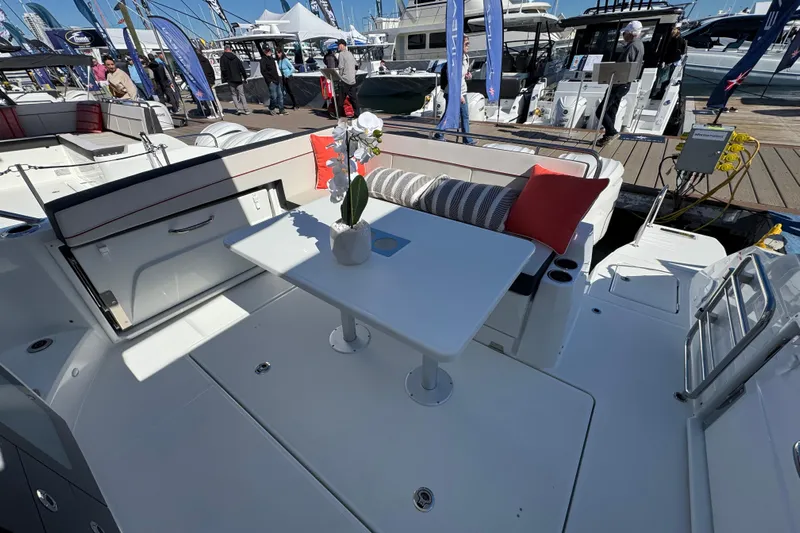  Yacht Photos Pics 2025 Jeanneau Leader 10.5 WA Series 2 boat interior with table and seating at a marina.