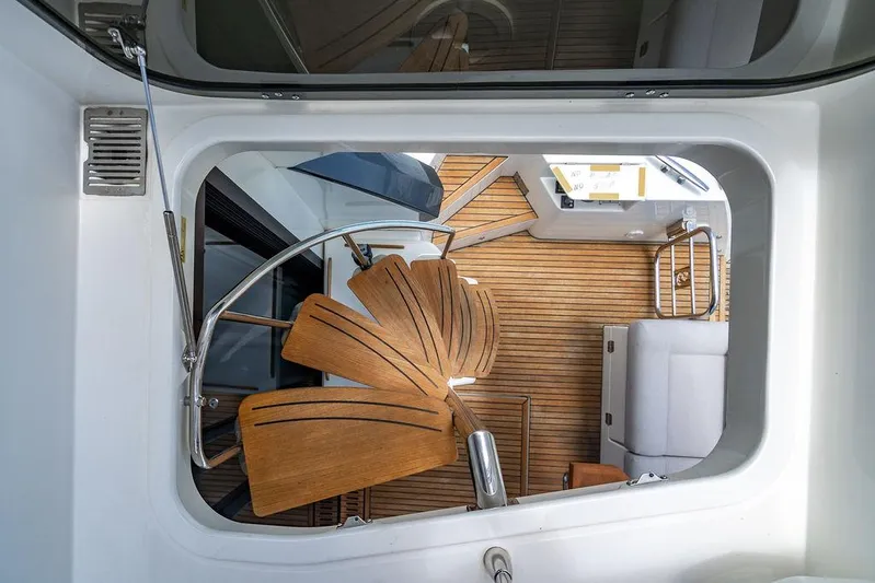 Grace Yacht Photos Pics Interior view of 2022 Beneteau Monte Carlo 52 yacht with spiral staircase and wooden flooring.