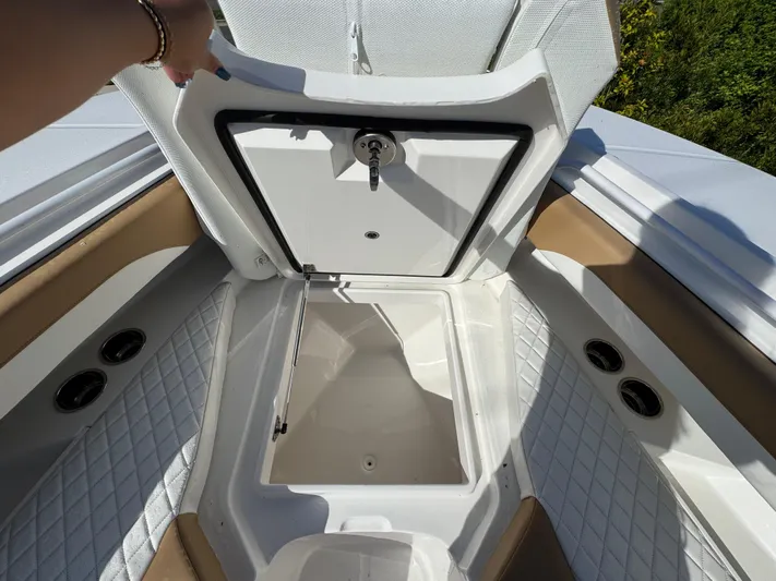 Yacht Photos Pics 2025 Regulator 31 boat storage compartment with open hatch, featuring quilted flooring and cup holders.