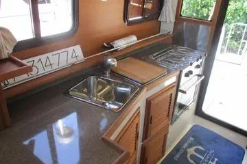  Yacht Photos Pics 2021 Ranger Tugs R-31 CB kitchen interior with sink, stove, and wooden cabinetry.