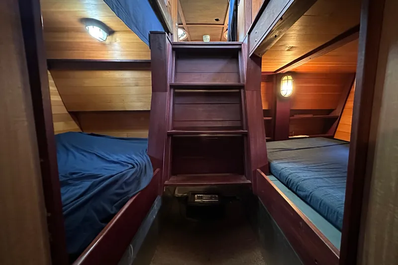 Lone Wolf Yacht Photos Pics Cozy wooden cabin interior of 2002 Carlson Marine Trawler with twin beds and warm lighting.