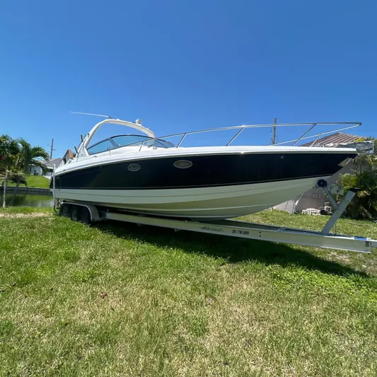  Yacht Photos Pics 2005 Formula 330 SS boat on trailer, parked on grass under clear blue sky.