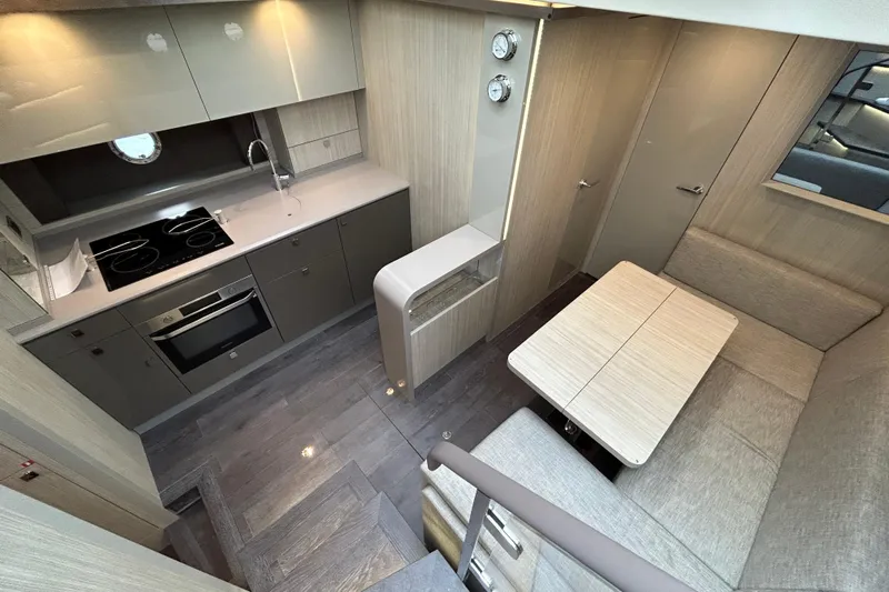  Yacht Photos Pics Modern kitchen and dining area in 2023 Cranchi 60 ST yacht, featuring sleek cabinetry and appliances.