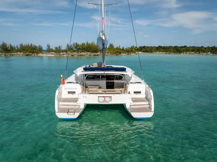 Watercolor Yacht Photos Pics 2023 Lagoon 46 catamaran anchored in clear turquoise waters near a tropical shoreline.