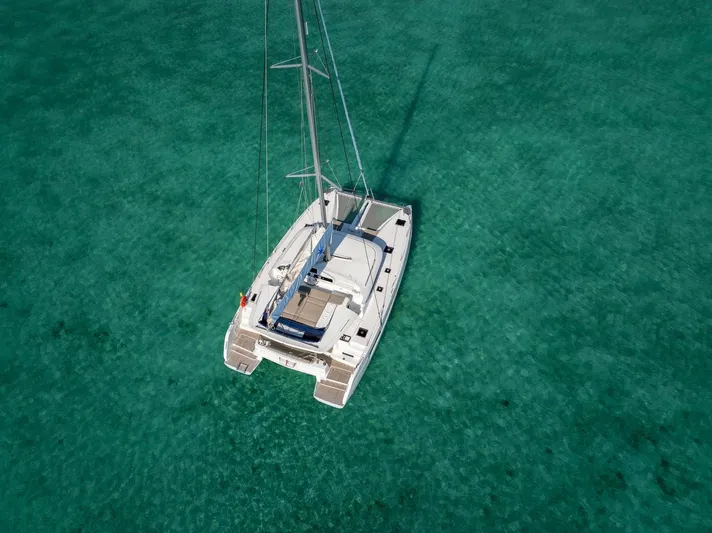 Watercolor Yacht Photos Pics 2023 Lagoon 46 catamaran sailing on clear turquoise waters, aerial view.