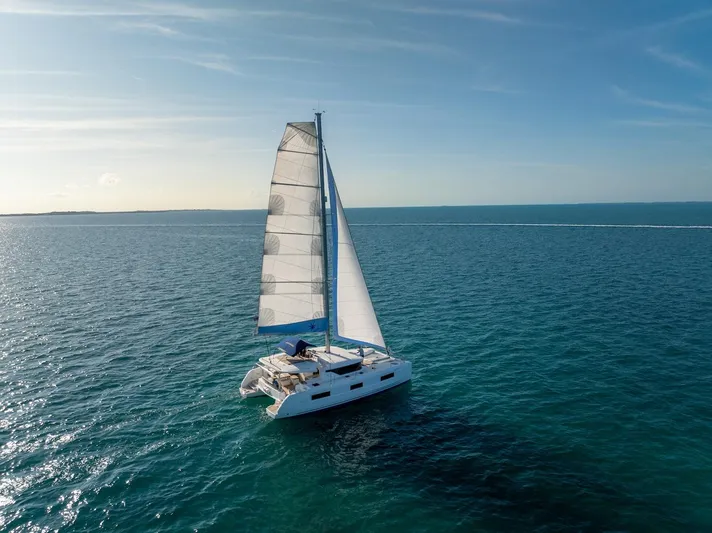 Watercolor Yacht Photos Pics 2023 Lagoon 46 catamaran sailing on open sea under clear blue sky.