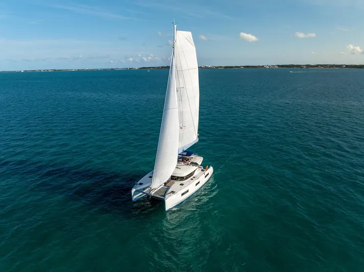 Watercolor Yacht Photos Pics 2023 Lagoon 46 catamaran sailing on open sea under clear blue sky.