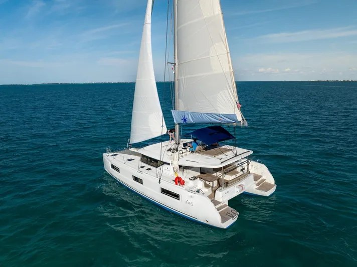Watercolor Yacht Photos Pics 2023 Lagoon 46 catamaran sailing on open sea under clear blue sky.