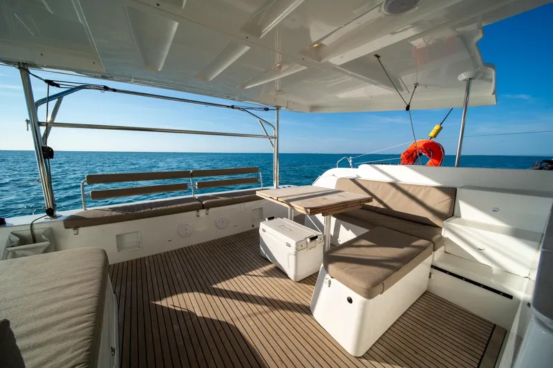 Watercolor Yacht Photos Pics 2023 Lagoon 46 catamaran deck with seating, table, and ocean view.