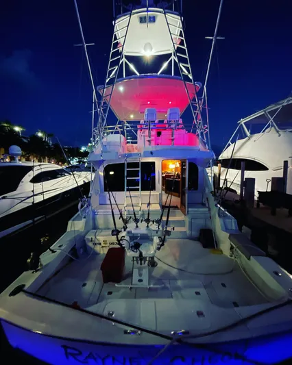Rayne Check Yacht Photos Pics 2001 Hatteras 65 yacht at night, illuminated with colorful lights, docked at marina.