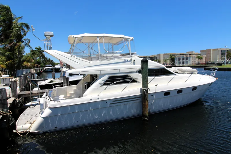 Empty Pockets Yacht Photos Pics 1997 Viking Sport Cruisers 48SC yacht docked by the waterfront under a clear blue sky.