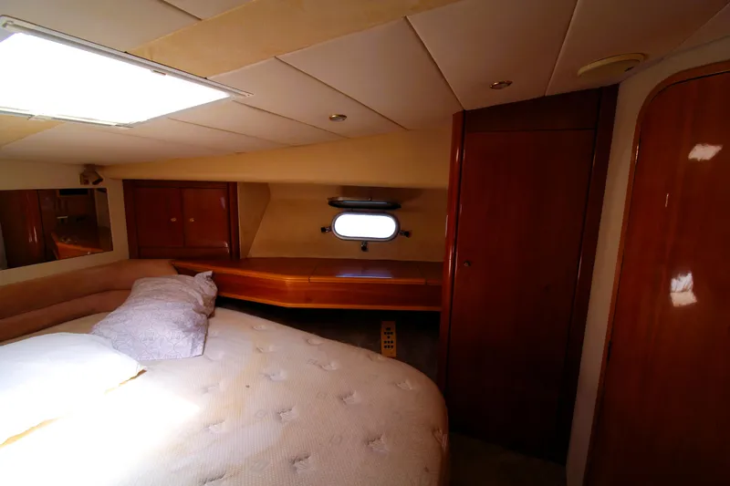 Empty Pockets Yacht Photos Pics 1997 Viking Sport Cruisers 48SC cabin interior with bed, wooden cabinetry, and porthole window.