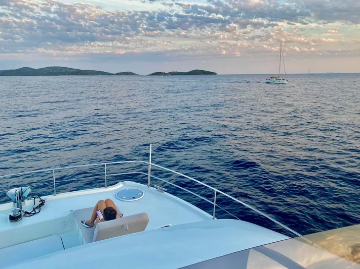 Yacht Photos Pics Person relaxing on a 2021 Fountaine Pajot MY6 yacht, enjoying a serene ocean view.