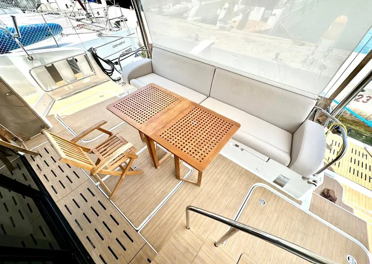  Yacht Photos Pics 2021 Fountaine Pajot MY6 yacht deck with wooden table, chairs, and cushioned seating.
