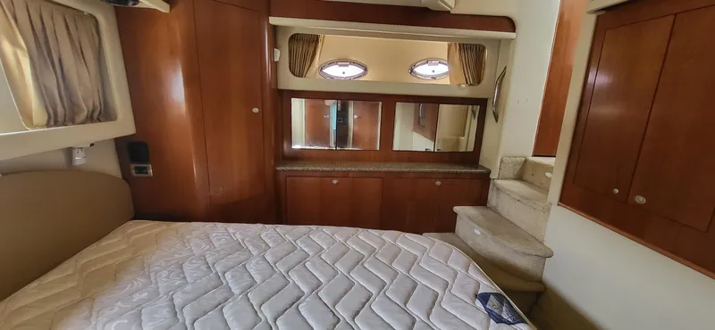  Yacht Photos Pics Interior of 2005 Sea Ray 390 Motor Yacht with bed, wooden cabinets, and porthole windows.