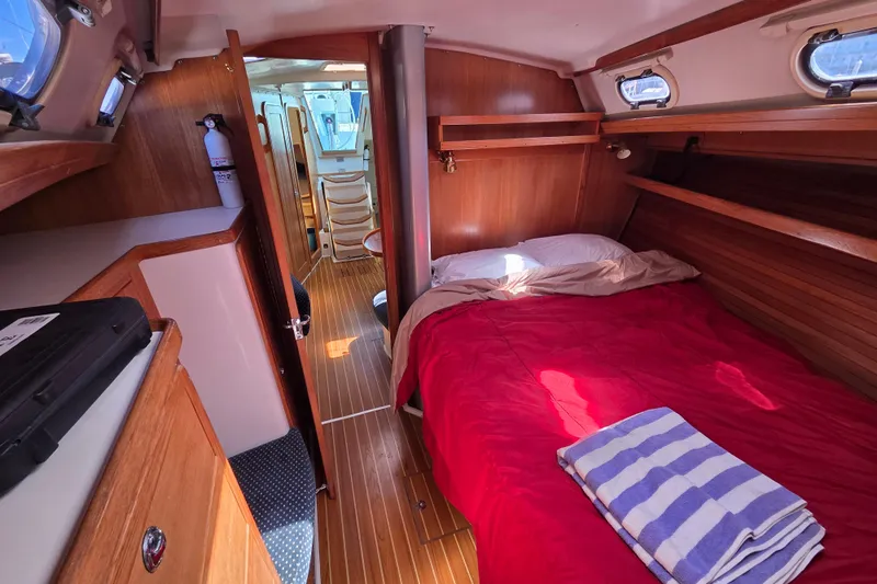  Yacht Photos Pics Cozy cabin interior of 2007 Catalina 42 MkII sailboat with red bedding and wooden finish.